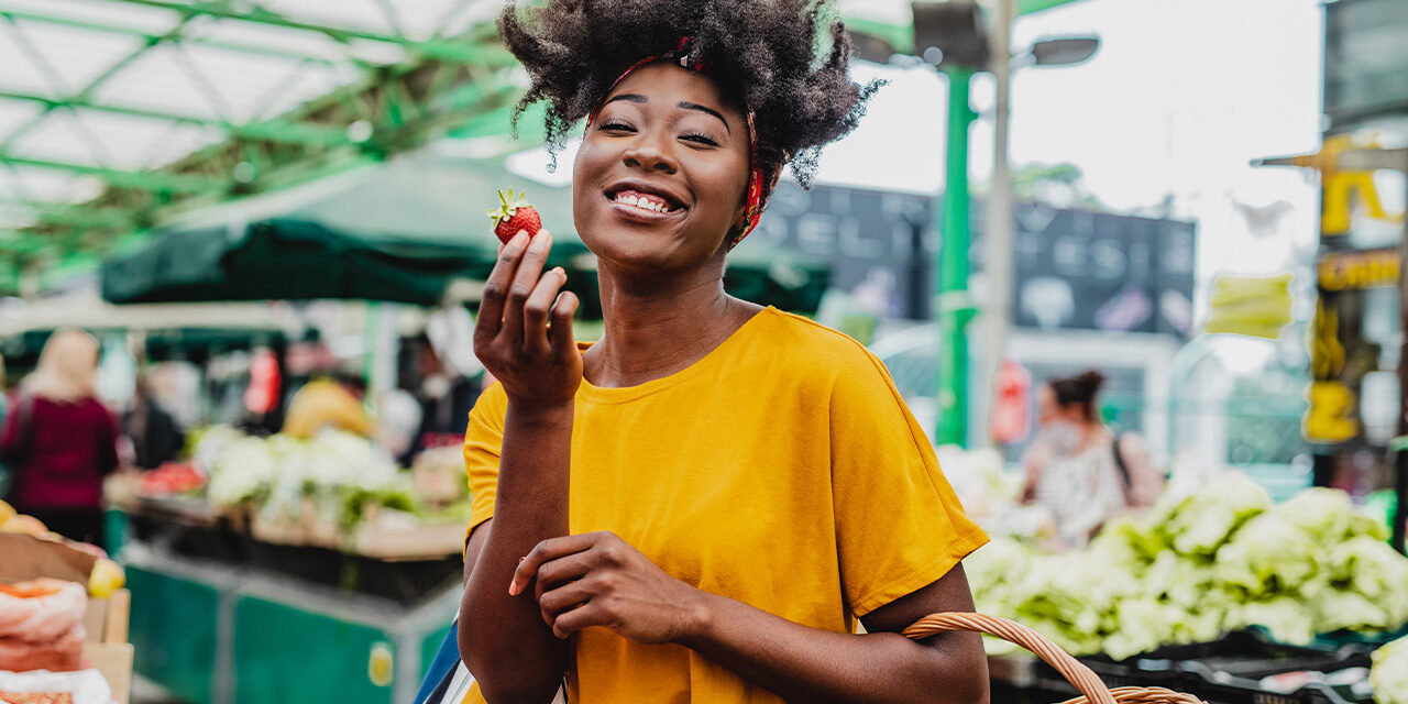 Woman enjoying a strawberry at the farmers market.