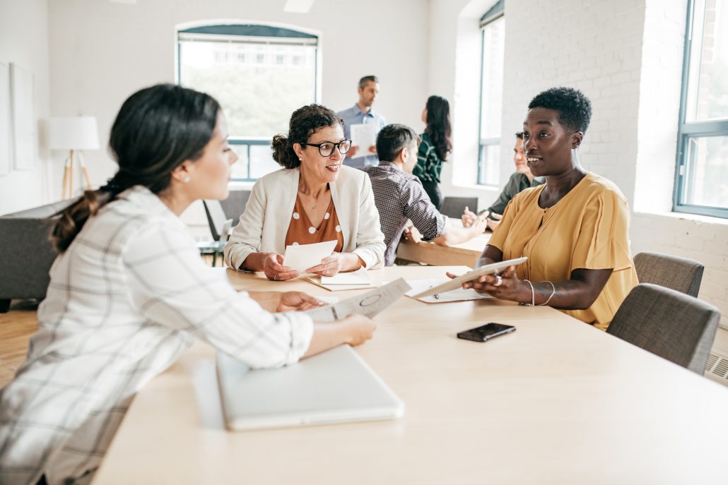 Women around a table discussing work.