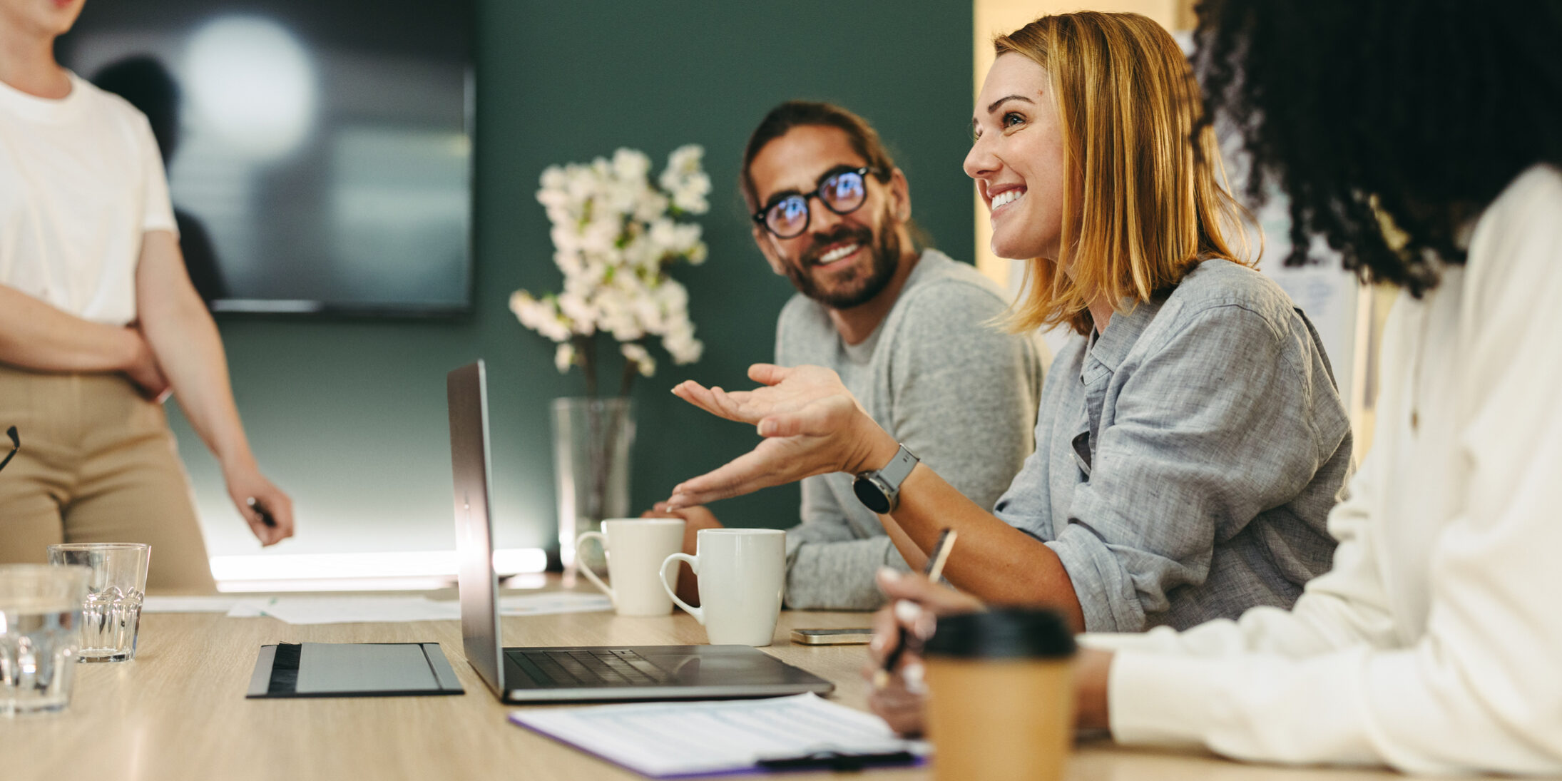 Business woman talking to her colleagues during a meeting in a boardroom. Group of happy business people working together in a creative office.