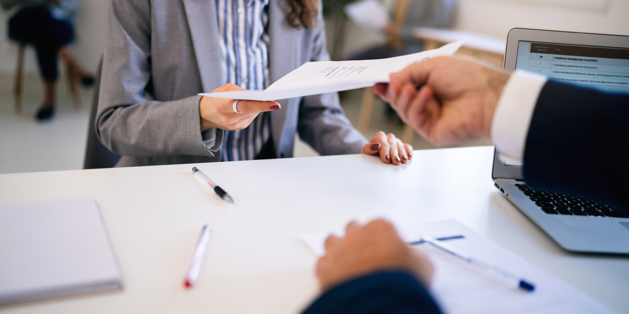 In the office young Caucasian female candidate, giving her CV or application form to male recruiter during a job interview
